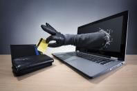 Black gloved hand coming through laptop screen to steal a credit card from a wallet