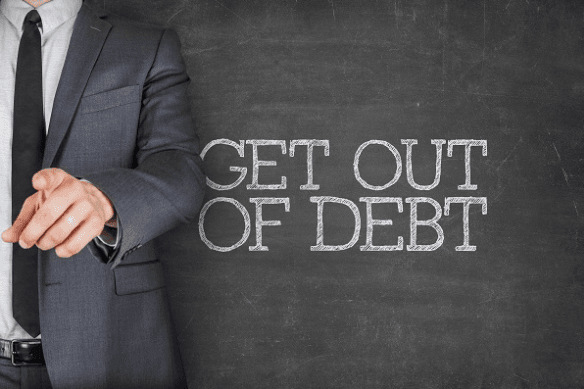 A person in a suit in front of chalk board with "Get out of debt" written on it